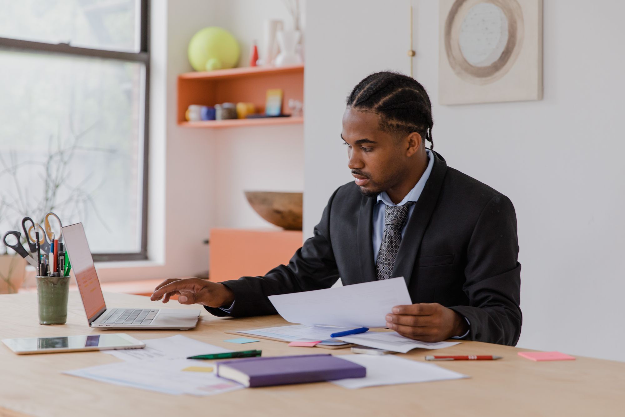 Business owner reviewing ethics hotline options with papers and a laptop at his desk